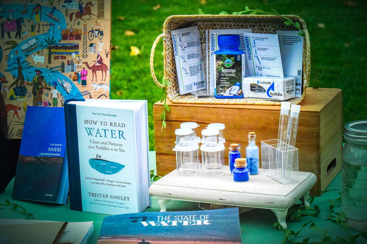 Books, maps, test tubes, and water testing kits are arranged on a table as part of an educational station about river health.